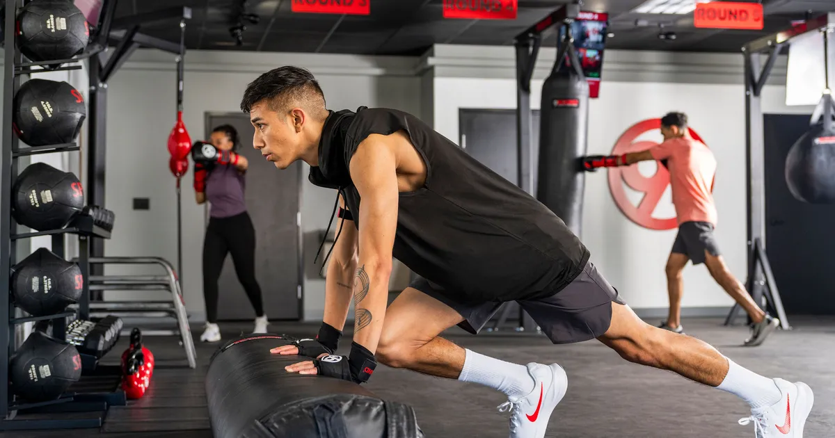 A trainer coaching a client through proper squat form in a well-lit gym